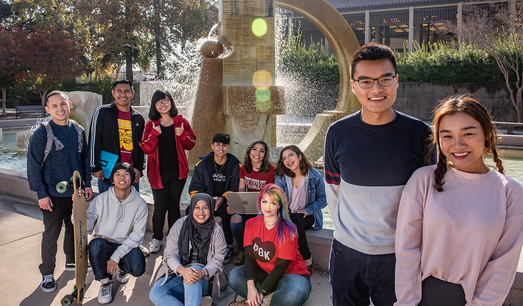 group of students smiling in front of fountain