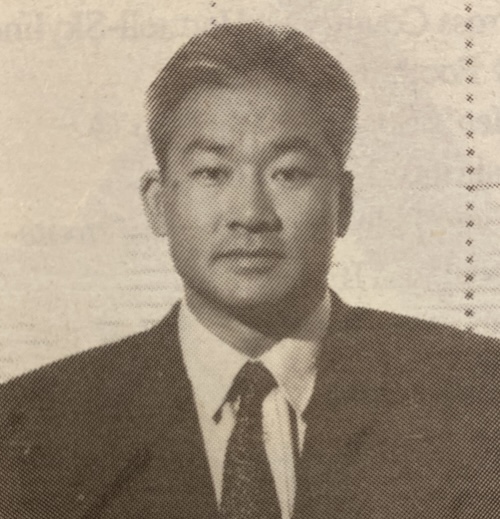 Black and white vintage photo of a person in a suit and tie with short hair.