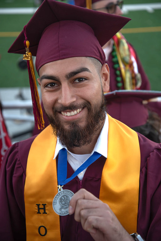 smiling young man in grad cap with honors medallion