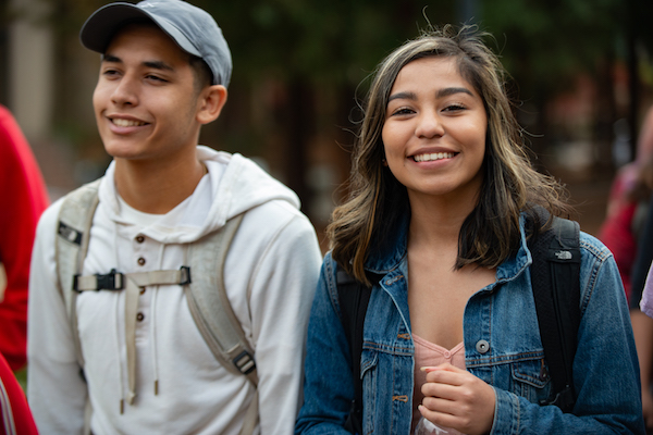 two students with backpacks, smiling