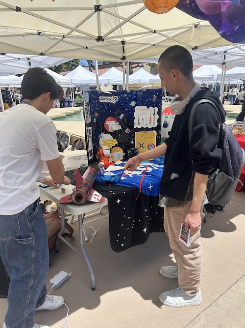 young men at outdoor table with posters