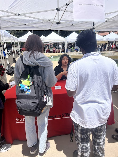young woman speaking to students at information table