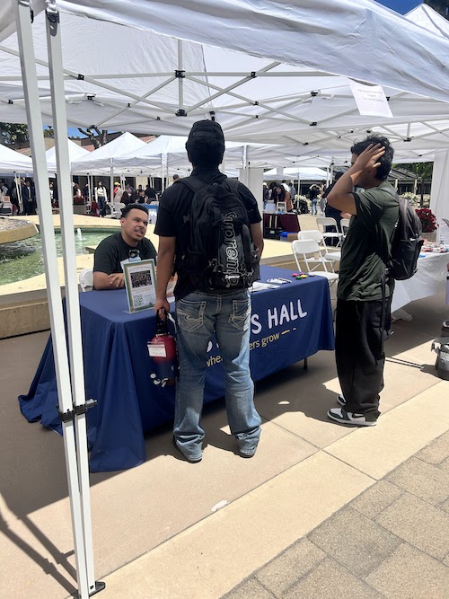 young man talking with students at info table