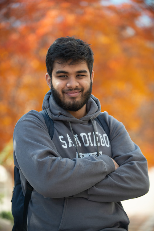 young man in sweatshirt, smiling with arms crossed confidently