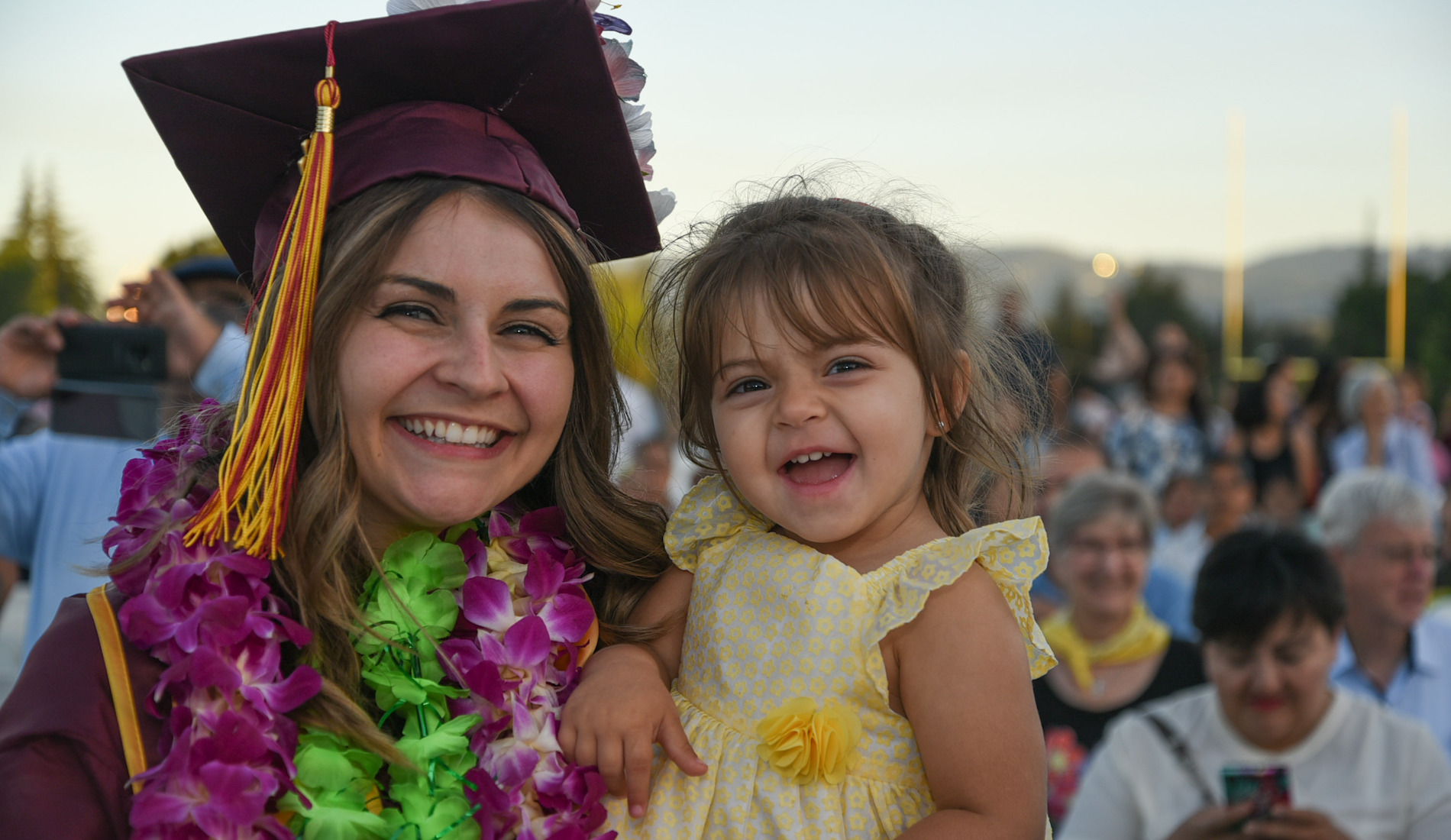 young woman in grad cap holding little girl