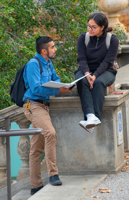 young man and young woman leaning on wall and talking