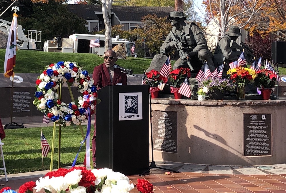 President Holmes at podium next to veterans' memorial